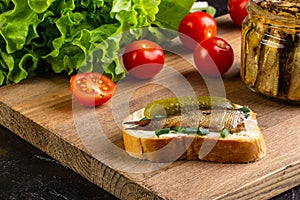 Sandwich with sprots and cucumber, on a board with tomatoes and salad