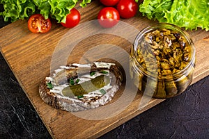 Sandwich with sprots and cucumber, on a board with tomatoes and salad