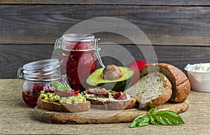 Sandwich with sun-dried tomatoes, avocado, basil, curd cheese on croutons. Vegetarian breakfast or snack