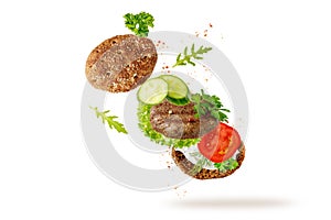 Sandwich toast  with grilled beef cutlet and fresh herbs and vegetables flying isolated on white