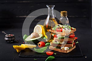 Sandwich toasts with tomatoes, mozzarella, avocado and basil