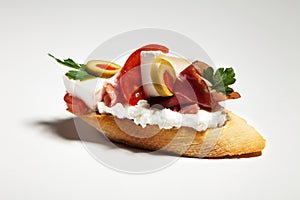 Sandwich with white cheese, parsley, olive, ham and tomato on white background