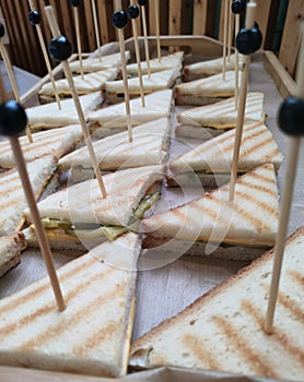 Sandwich on wooden skewers. The filling of the sandwich consists of bacon, cheese and salad