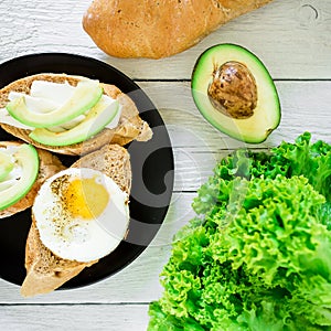 Sandwiches with avocado and egg on a dark plate on rustic background. Flat lay. Top view. Tasty breakfast for vegan