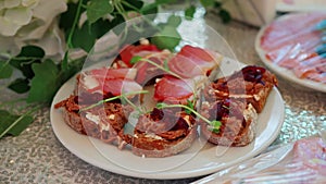 Sandwiches with black bread, meat and ham in a plate on a festive table in a restaurant. Slow motion