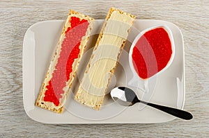 Sandwiches with butter and imitation salmon caviar, spoon, bowl with caviar in plate on table. Top view