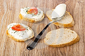 Sandwiches with cheese, tomato and dill, spoon with cheese on bread on wooden table