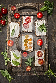 Sandwiches with cheese tomatoes fresh herbs on a wooden cutting board on rustic wooden background top view homemade