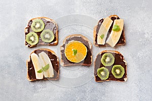 Sandwiches with chocolate paste and various fruits on a gray table. Top view. Concept delicious Breakfast