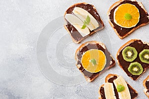 Sandwiches with chocolate paste and various fruits on a gray table. Top view. Concept delicious Breakfast. Copy space