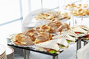 Sandwiches croissants on the buffet table. Coffee break and business meetings. Close-up