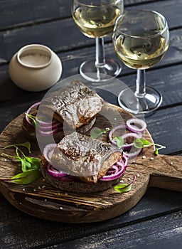 Sandwiches with grilled fish and quick pickled onions and two glasses of white wine