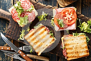 Sandwiches with grilled toast ham salami cheese tomatoes and lettuce