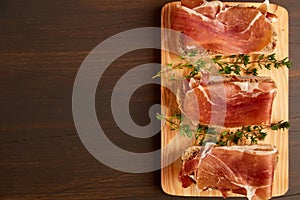 Sandwiches made from hand-made rye bread and thin chopped fresh bacon. Fresh green thyme on a wooden board. Succulend bacon on a w
