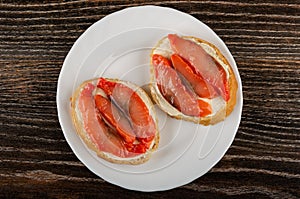 Sandwiches with pink salmon and butter in plate on wooden table. Top view