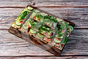 Sandwiches with red salmon fish on thin wheat bread for dietary nutrition, fresh cucumber, lemon and dill greens are visible in