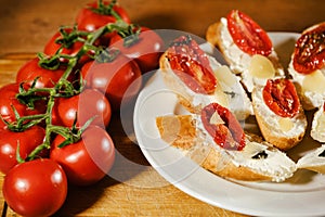 sandwiches with red sun-dried tomatoes and cheese on a plate on the table next to fresh tomatoes