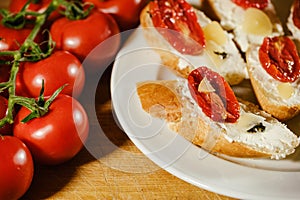 sandwiches with red sun-dried tomatoes and cheese on a plate on the table next to fresh tomatoes