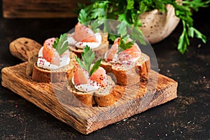 Sandwiches with salmon. Canape with red fish, rye bread, soft cheese, parsley and spices. Selective focus.