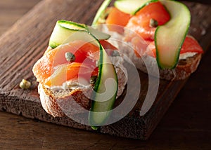 Sandwiches with smoked trout, cream cheese, fresh cucumber, and capers on a cutting board