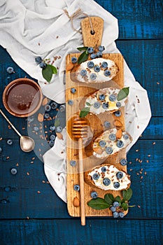 Sandwiches with soft cheese and blueberries on a wooden background. A healthy breakfast
