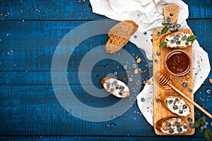 Sandwiches with soft cheese and blueberries on a wooden background. A healthy breakfast