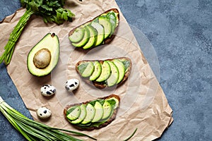 Sandwiches toast with avocado, guacamole and spinach on parchment on a concrete background. Healthy breakfast or lunch