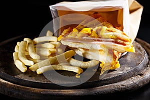 Sandwish ham cheese with frenchfries on wood plate and black photo