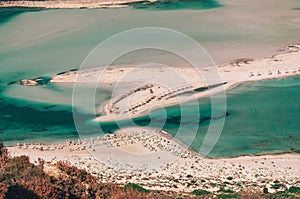 Sandy Balos beach with umbrellas and lagoon with clear blue water at Crete island, Greece.