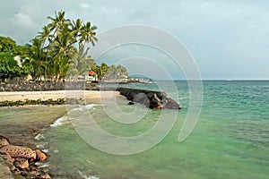 Sandy beach with azure ocean and palm trees during the storm