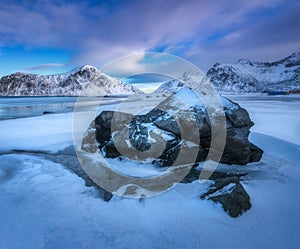 Sandy beach with blue sea reflected in water and rocks in snow