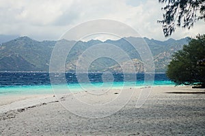 Sandy beach with blue water on the tropical island of Gili Meno. The mountains of Lombok on the horizon