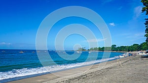 Sandy beach with calm ocean waves in Bali with clear blue sky