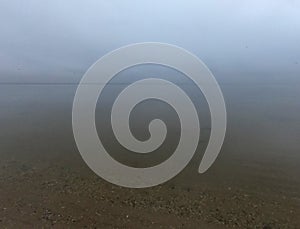 Sandy beach on calm sea. Calm sea cloudy weather. Smooth waveless sea surface