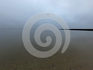 Sandy beach on calm sea. Calm sea cloudy weather. Smooth waveless sea surface