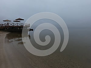 Sandy beach on calm sea. Calm sea cloudy weather. Smooth waveless sea surface photo