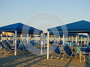 Sandy beach dotted with umbrellas and chairs