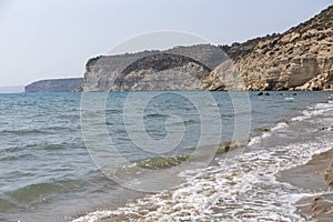 Sandy beach with gentle waves on the Cyprus coast, showcasing cliffs