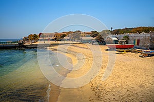 Sandy beach on Goree Island with colorful buildings and boats