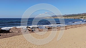 Sandy beach of Mediterranean Sea with dark blue waves splashing in sunrays. Wide shot of Cyprus tourist resort on sunny