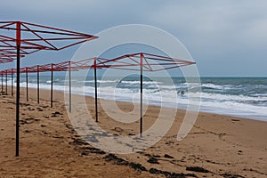 Sandy beach with metal umbrellas. A deserted beach with a stormy sea