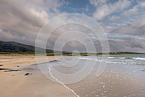 Sandy beach and ocean waves rushing towards the land. Irish nature landscape, Atlantic ocean,West coast of Ireland. Cloudy sky