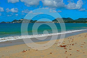 Sandy beach and pale blue sea on the coast of the Caribbean island of Saint Lucia.