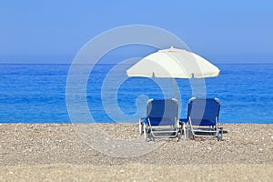 Sandy beach with parasol and two sunbeds