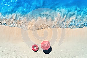 Sandy beach with red swim ring and umbrella at sunset. Top view