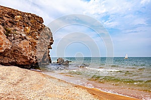 Sandy beach, rock. White ship on the turquoise water of the sea. Copy space.