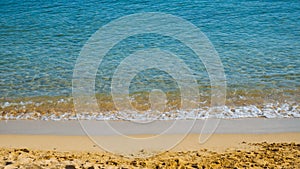 Sandy beach with small waves - blue sea and yellow sand