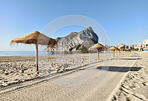 Sandy beach with straw parasols in Calpe. Spain