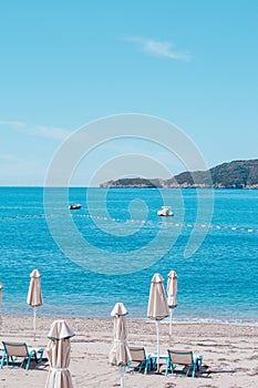 Sandy beach with sun beds and umbrellas on sunny day. Sunny vacation concept on beach, Montenegro.