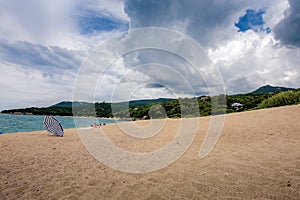 A sandy beach with a sun umbrella.